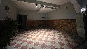 Un grand espace intérieur doté d’un sol à carreaux, d’un ventilateur de plafond et d’un luminaire fixé au mur.