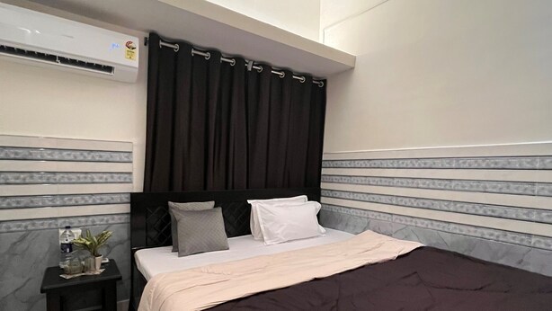 Un dormitorio con cama, mesita de noche, planta en maceta y equipo de aire acondicionado.