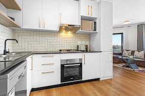 Une cuisine compacte dotée d’appareils électroménagers intégrés, d’un dosseret orné d’un motif en chevrons et d’un design moderne.