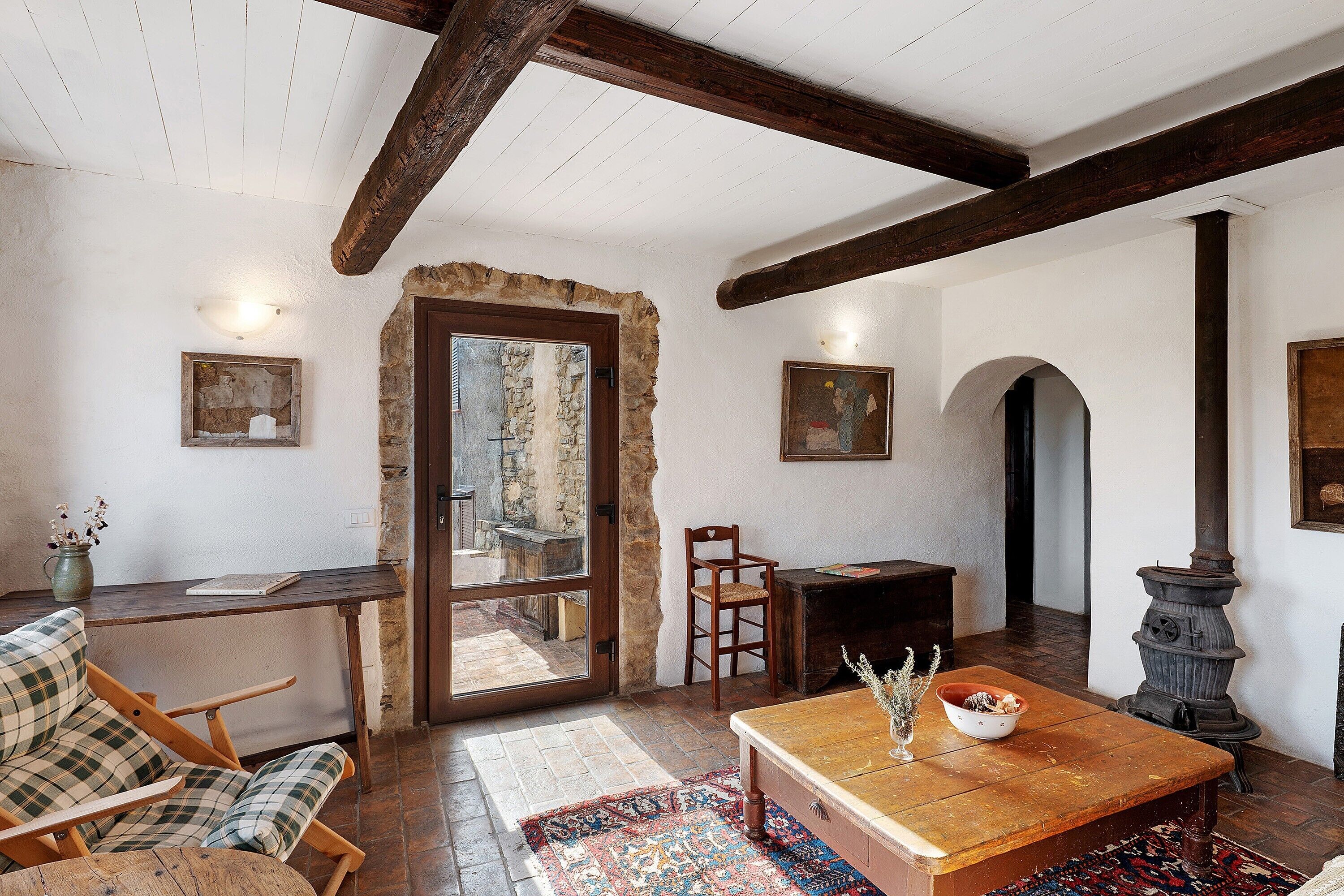 Un interior rústico con vigas de madera a la vista, una pared de piedra, una mesa de madera, un sofá y una chimenea.
