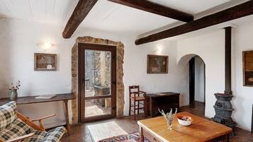 Un interior rústico con vigas de madera a la vista, una pared de piedra, una mesa de madera, un sofá y una chimenea.