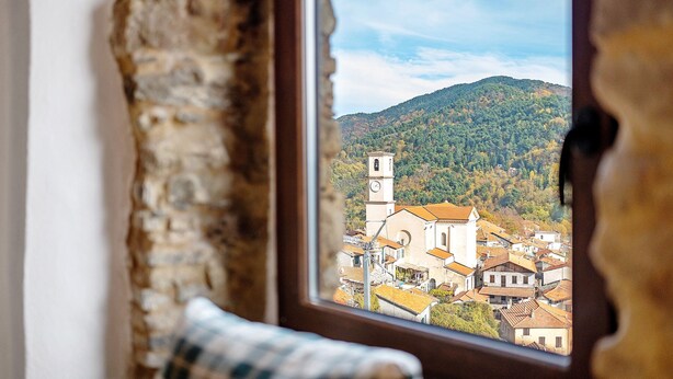 Una ventana con vista a un pueblo, una torre del reloj y una montaña.