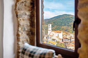 A window with a view of a town, a clock tower, and a mountain.