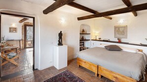 Un dormitorio con una cama de madera, una chimenea de piedra y un techo rústico.