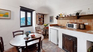 Una cocina compacta con comedor, un refrigerador pequeño y un microondas.