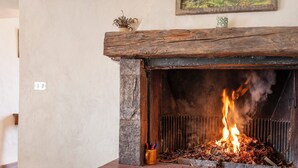 A fireplace with burning logs, a stone wall, and a small plant on the mantel.