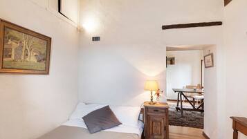 Ein Schlafzimmer mit einem Bett, einem Nachttisch mit Lampe, einem Bild an der Wand und Holzboden.