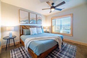 A bedroom with a bed, a ceiling fan, a window with blinds, and a small table with a lamp. - Mountain Views Retreat|Hot Tub • Views • Game Room (Sevierville)