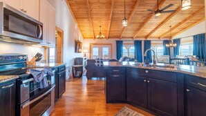 Una cocina moderna con armarios oscuros, electrodomésticos de acero inoxidable y techo de madera.