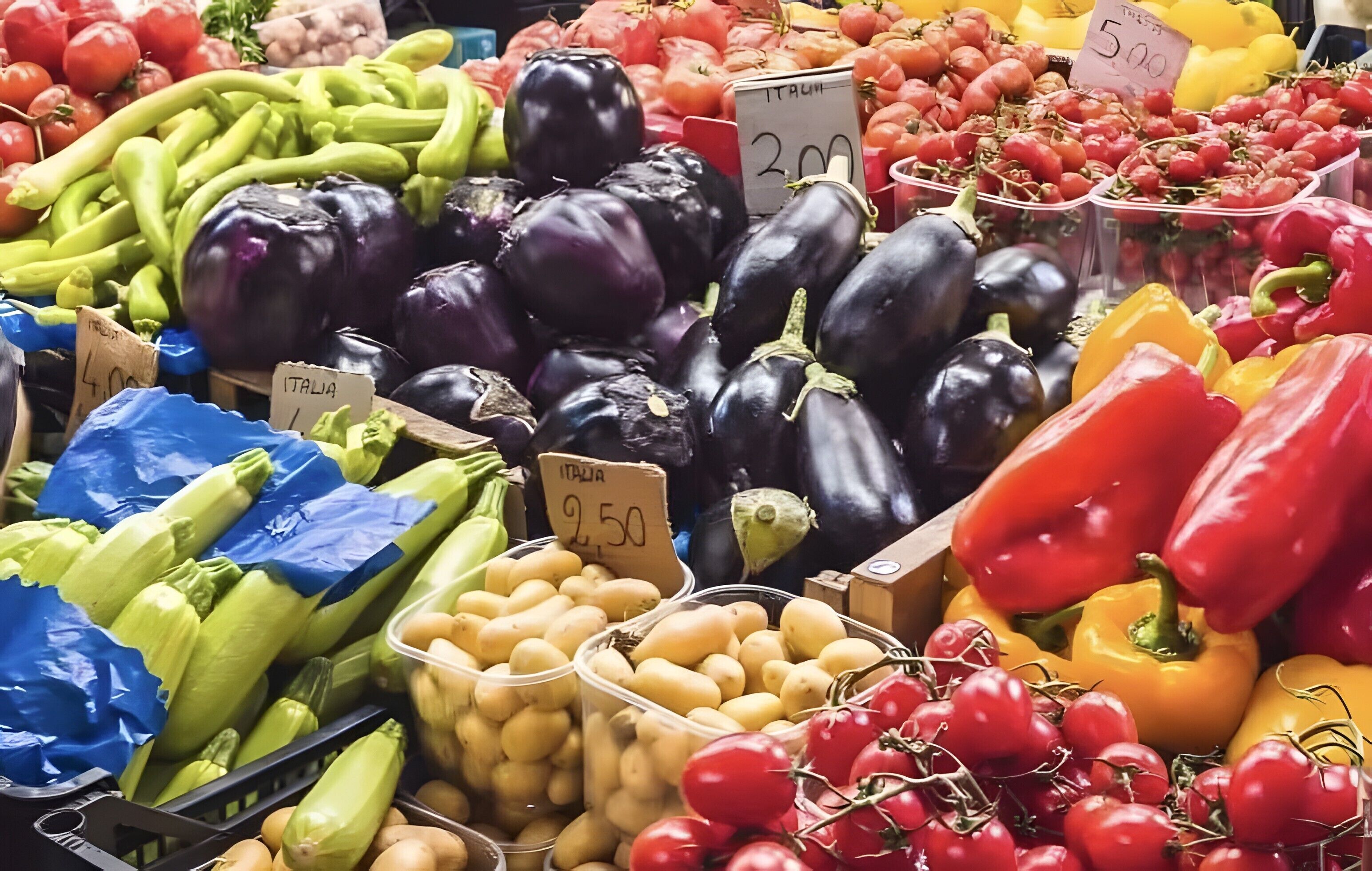 Variedad de verduras frescas, como berenjenas, tomates y pimientos, en un mercado.