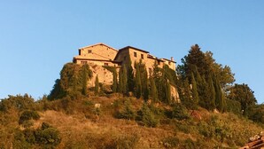 Ein steinhaueres Gebäude mit Flachdach, umgeben von Bäumen auf einem Hügel.