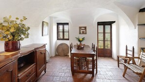Ein Essbereich mit Holztisch und -stühlen, einem Blumentopf und einer großen Holztür.