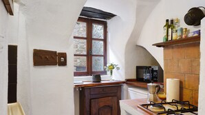 Eine Küche mit Gasherd, Mikrowelle, einem Fenster mit Aussicht und einem Regal mit Flaschen.
