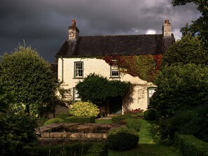 Ein traditionelles Steinhaus mit einem Vorgarten, mit einem Steinweg und einem kleinen Teich.