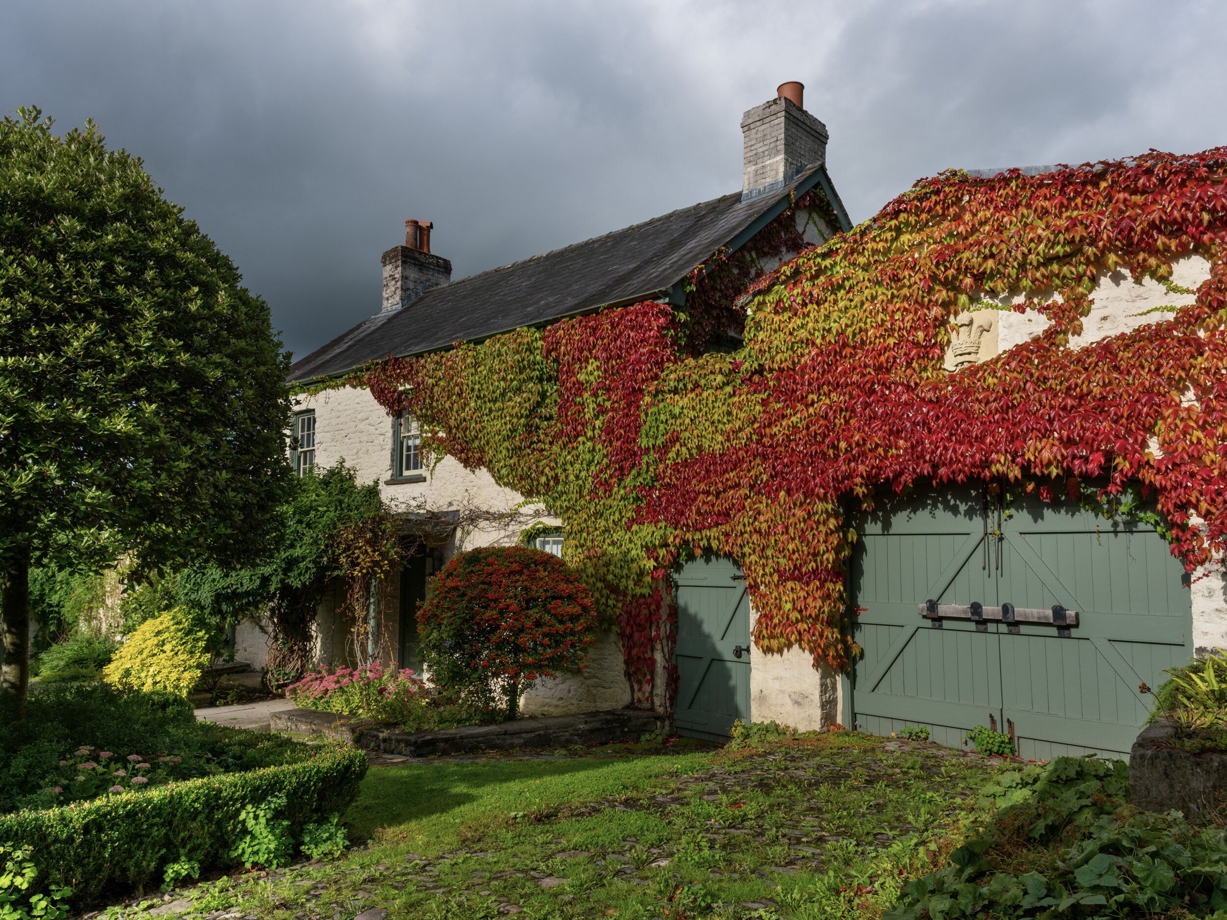 A traditional stone house with ivy-covered walls and a green door.
