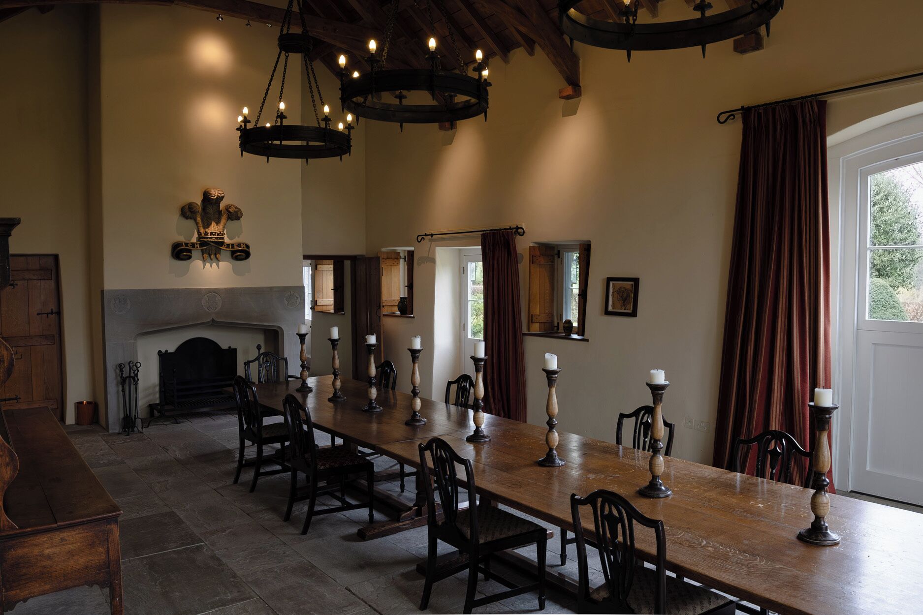 A dining room with a long wooden table, multiple chairs, a fireplace, and a chandelier.