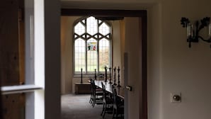 A dining area with a table and chairs, a stained glass window, and a door leading to another room. - West Cottage (Llandovery)