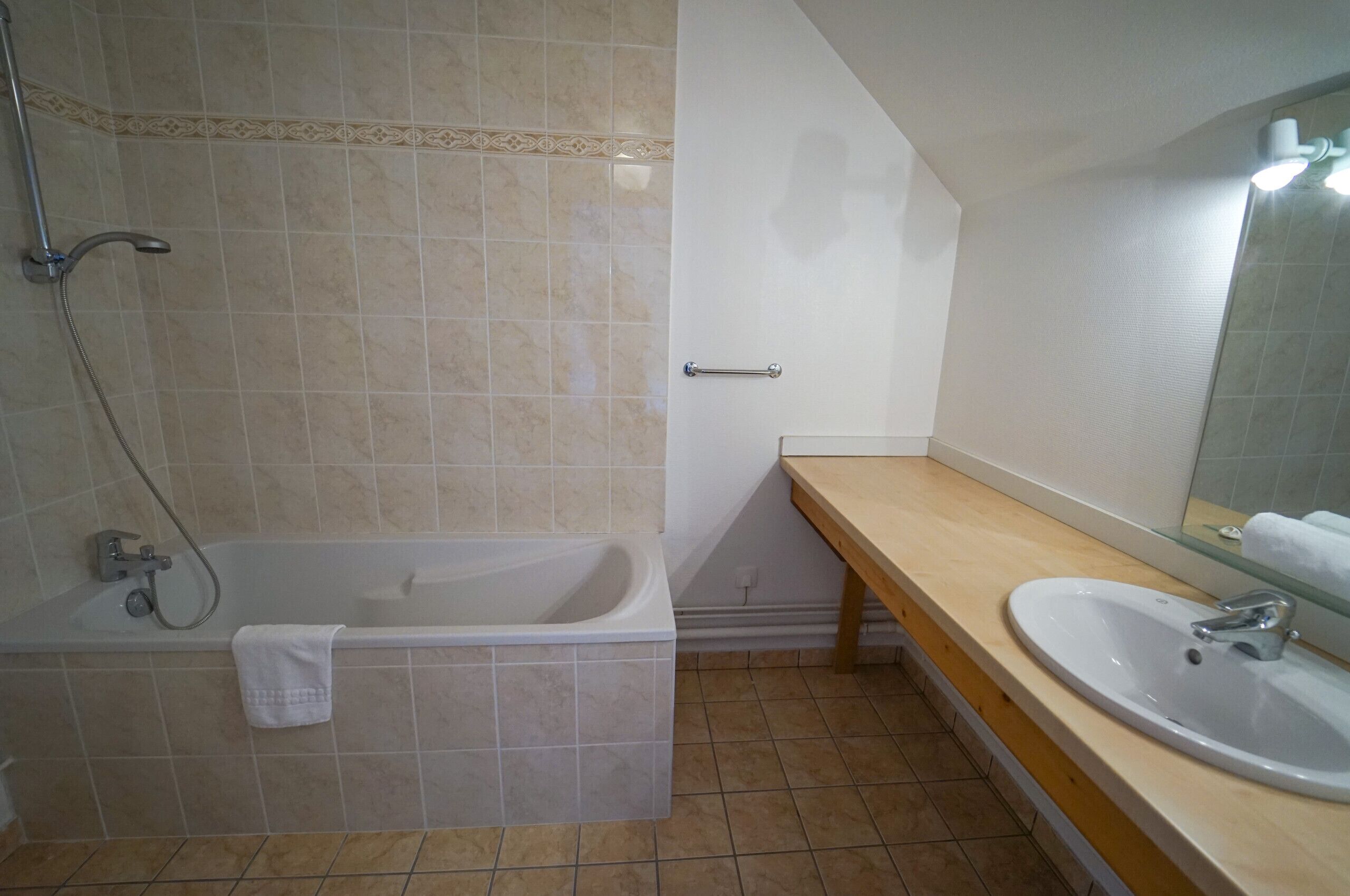 A bathroom with a bathtub, a sink, and a mirror.
