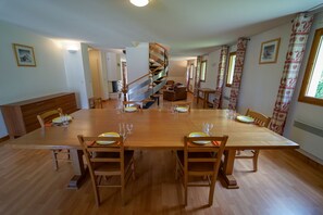 A spacious dining area with a large wooden table, chairs, and a spiral staircase.
