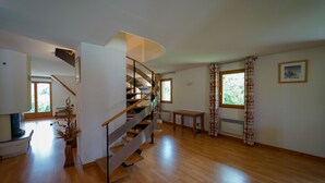 A spacious living area with a wooden floor, a spiral staircase, and large windows. - Duplex apartment, sleeps 10, nature view (Giez)
