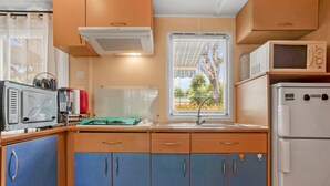 A compact kitchen with a sink, a microwave, a refrigerator, and cabinets. - Mobile Home for 6 with Private Terrace, Wi-Fi & Air Conditioning in Hyères (Hyères)