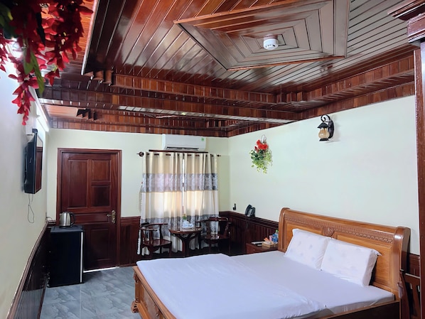 Un dormitorio con techo de madera, una cama, un escritorio y una silla.