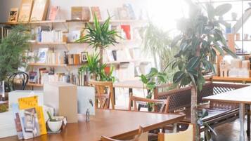 Una habitación con una mesa de madera, sillas, una estantería y plantas en macetas.