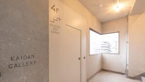 Un couloir avec une porte portant l’inscription « 4F HAJIMARI ROOF GARDEN » et « KAIDAN GALLERY ».