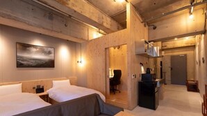 Une chambre d’hôtel avec deux lits, un canapé, une table en bois, un coin cuisine et un tableau au mur.