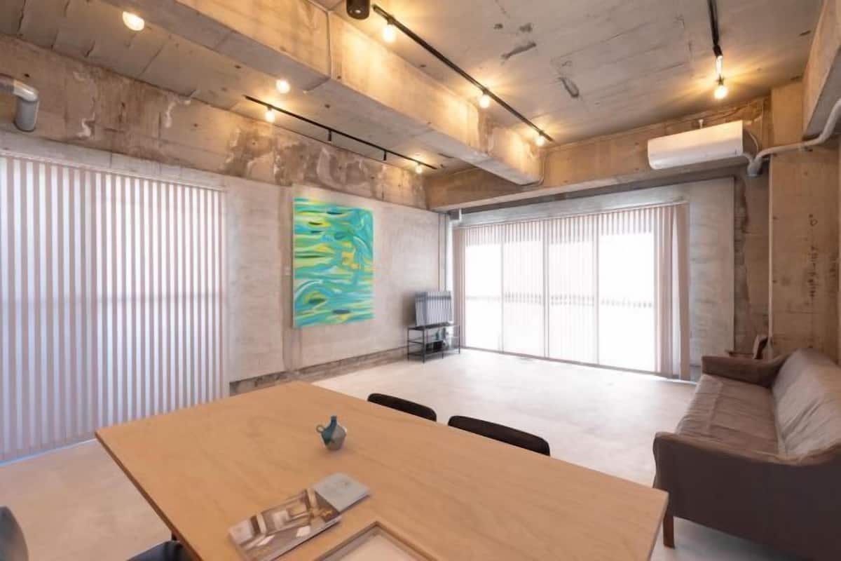 A spacious room with a wooden table, a sofa, and a large window.