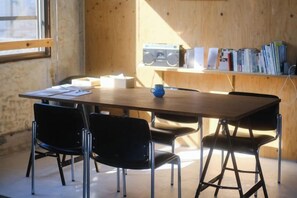 A wooden-paneled room with a table, chairs, a radio, and books. - HAJIMARI Beppu (Beppu)