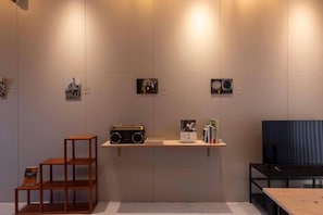 A room with a wooden chair, a shelf with books and a radio, and a black couch. - HAJIMARI Beppu (Beppu)