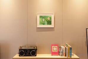Une pièce avec une radio, un tableau encadré et une bibliothèque remplie de livres.