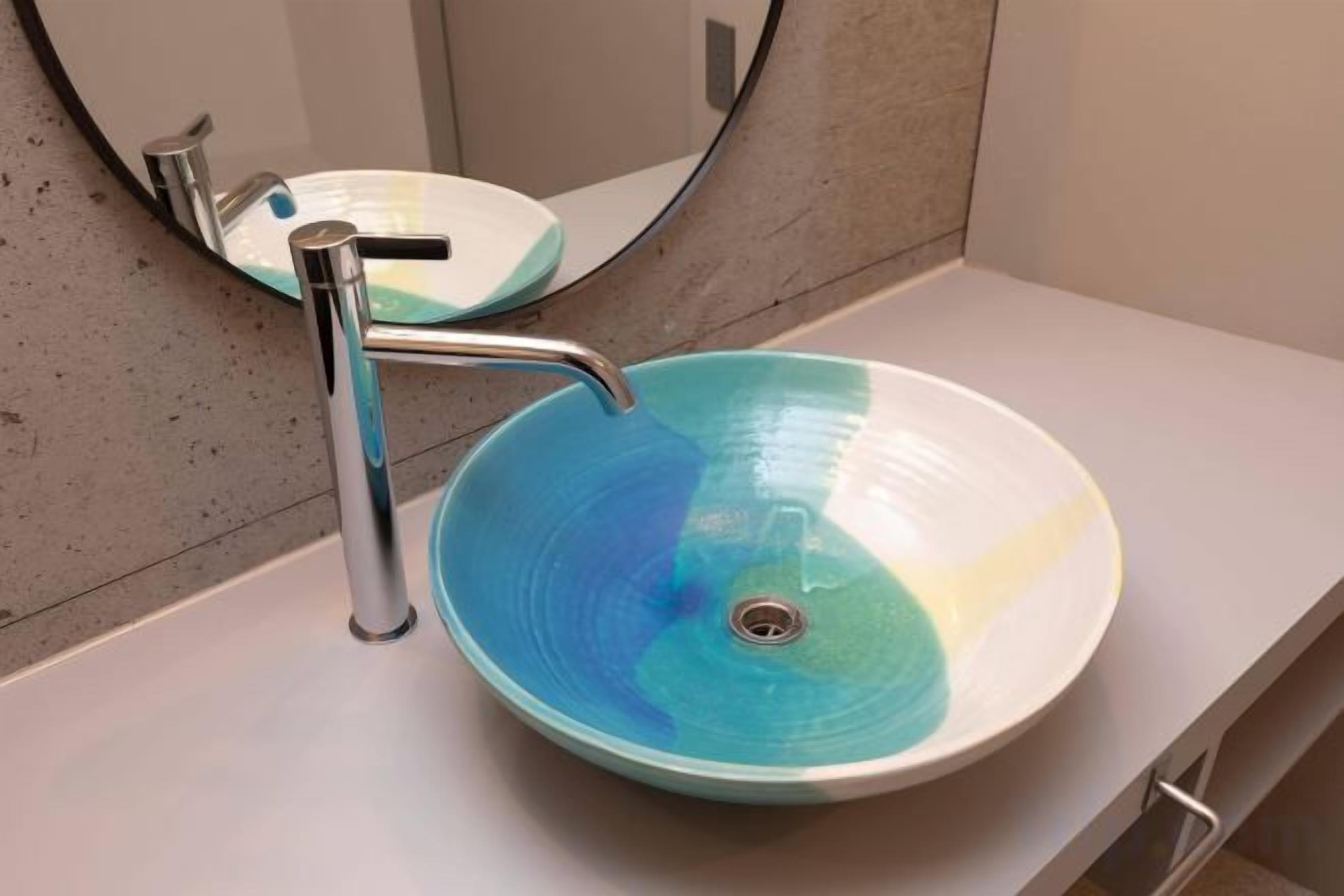 A bathroom with a round, blue glass sink, a chrome faucet, and a mirror above the sink.