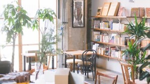 Une librairie chaleureuse avec des étagères en bois remplies de livres, quelques tables et des chaises.