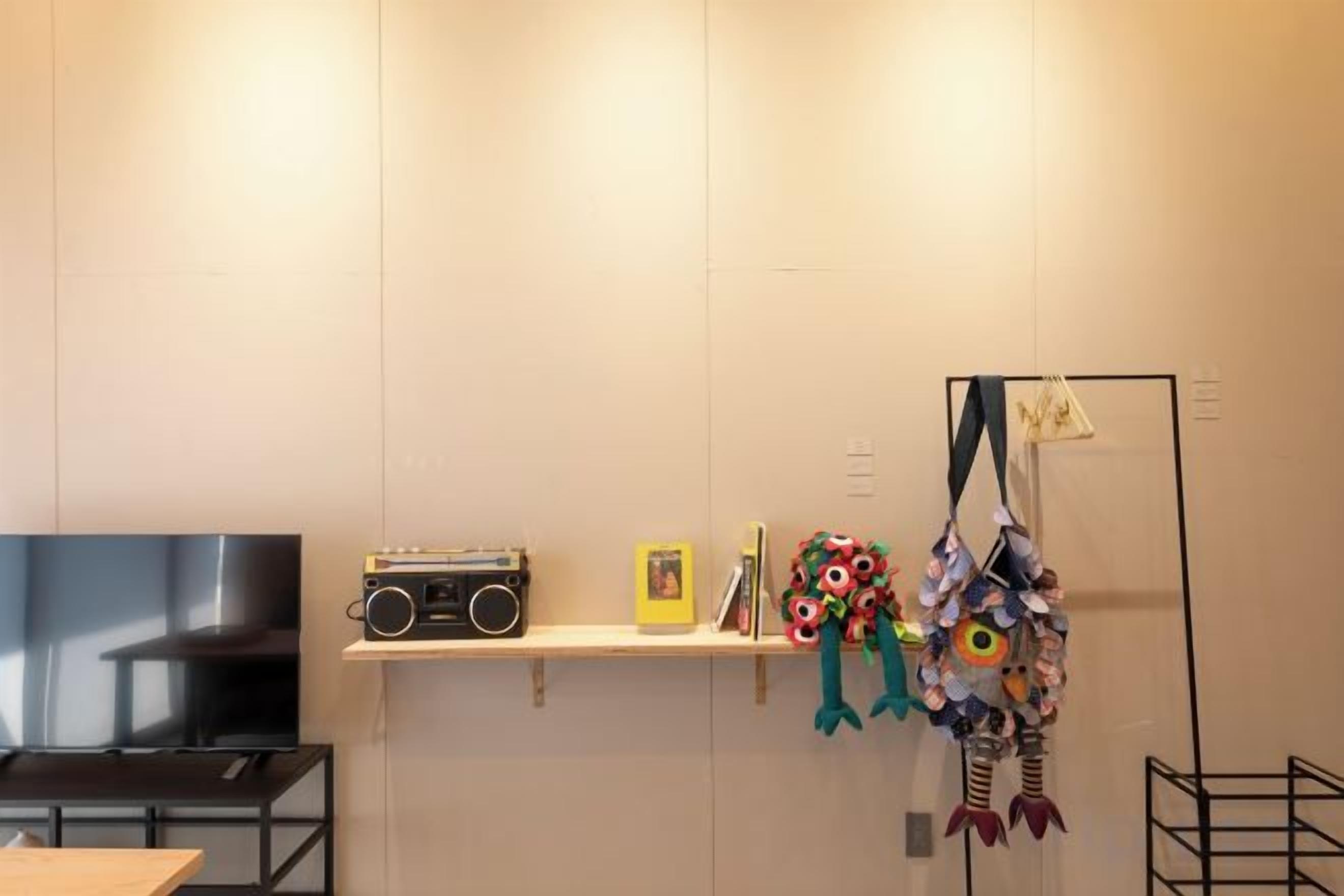 Una habitación con televisor de pantalla plana, estante con radio, marco de foto y objetos decorativos.
