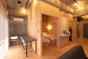 Habitación compacta con cama, escritorio y silla, paredes de madera y techo con vigas a la vista.