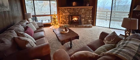 A cozy living room with a stone fireplace, leather sofas, and a Christmas tree.