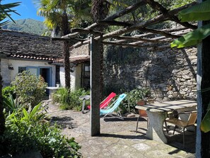 A stone wall, a hammock, and a patio area with chairs and a table. - Casa del Prete (Cannero Riviera)