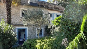 A stone house with a garden, a visible door, and a window with blue shutters. - Casa del Prete (Cannero Riviera)