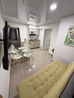 Espaço compacto com área de refeições, cozinha compacta e sofá.
