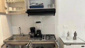 A compact kitchen with a sink, stove, blender, and a small refrigerator. - Apartamento loft cali (Cali)
