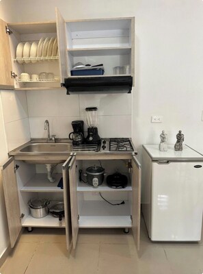 A compact kitchen with a sink, stove, blender, and a small refrigerator. - Apartamento loft cali (Cali)
