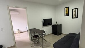 A modern living room with a sofa, a TV, a dining table with chairs, and artwork on the walls. - Apartamento loft cali (Cali)
