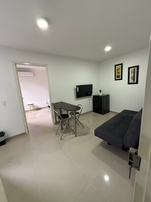 A modern living room with a sofa, a TV, a dining table with chairs, and artwork on the walls. - Apartamento loft cali (Cali)
