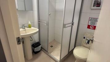 Une salle de bain avec une douche à parois de verre, un lavabo et des toilettes.