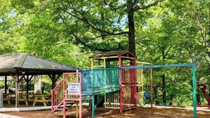 Un parque infantil con estructuras de juego coloridas y una zona de estar cubierta.