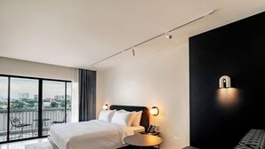 Ein modernes Hotelzimmer mit einem großen Bett, einem runden Tisch, einer Couch und einem Balkon mit Blick auf die Stadt.