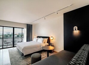 A modern hotel room with a large bed, a round table, a sofa, and a balcony with a city view. - The Standardx, Bangkok Phra Arthit (Bangkok)
