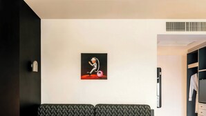Ein modernes Zimmer mit einer Couch, einem kleinen Tisch mit einem Buch und einer Tasse, einem Bild an der Wand und einem Kleiderschrank.